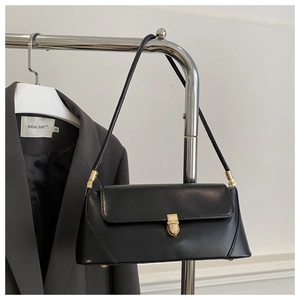 Detail of minimalist black baguette bag with retro golden metal lock on a clothes hanger