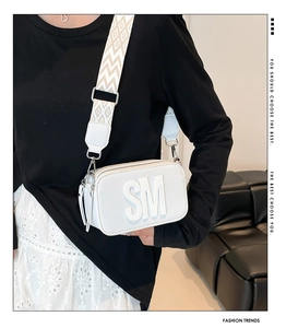 Détail du sac bandoulière blanc avec logo embossé et bandoulière à motif géométrique