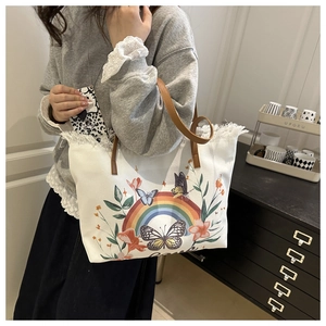 Gros plan du sac fourre-tout en toile avec imprimé papillon arc-en-ciel et anses en cuir