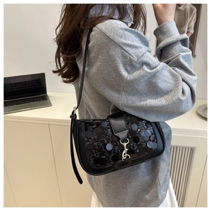 Detail of black sequined underarm bag with gold metallic buckle and leather texture
