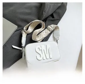 Gros plan d'un sac photo blanc avec bandoulière géométrique sur surface texturée