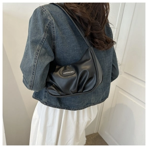 Close-up of black pleated hobo bag with Fashion & Bag patch worn on a shoulder