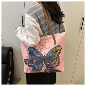 Detail of pink canvas tote featuring a large colorful butterfly print and brown leather strap