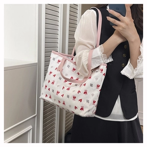 Detailed view of a white tote bag featuring heart patterns and pink bear illustrations