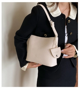 Close-up of cream pebble grain leather tote bag with embossed brand logo on shoulder