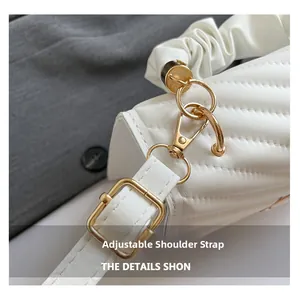 Close-up of white leather bag with V-quilted pattern and adjustable gold metal hardware