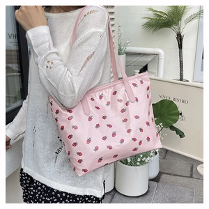 Detailed shot of a large pink tote bag with strawberry prints worn by a model