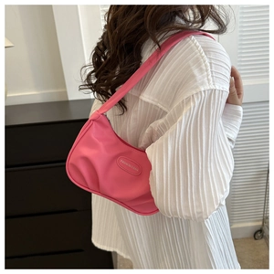 Detailed view of a pink crescent-shaped shoulder bag on a model wearing white shirt