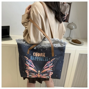 Détail du sac cabas en denim bleu avec broderie papillon et texte Choose Happiness