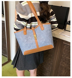Detail shot of blue denim tote bag with brown leather trim and golden metal turn-lock
