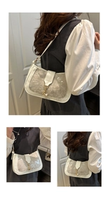 Detail of white sequin shoulder bag with golden metal clasp and white PU leather trim