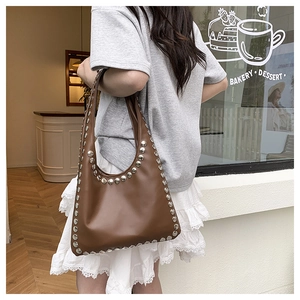 Detailed view of brown leather hobo bag with vintage silver studs on shoulder strap