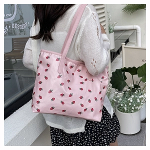 Close-up of pink tote bag with strawberry print being worn as a shoulder bag