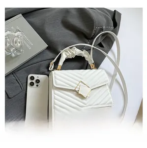 Detail of white V-quilted handbag featuring a gold square buckle and ruched handle
