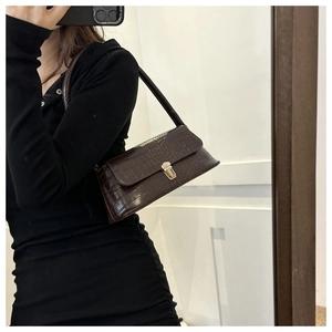 Detailed close-up of dark brown crocodile pattern handbag with gold metal clasp