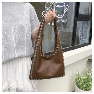 Detailed view of silver metallic studs on a vintage brown leather crescent shoulder bag