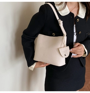 Side view of a beige pebble leather bucket bag worn with an elegant outfit