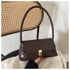 Close-up of a dark brown crocodile pattern baguette bag with a gold metal push-lock
