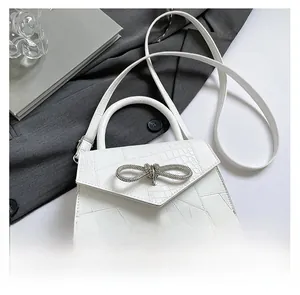 Detail of white crocodile pattern leather bag with sparkling rhinestone bow decoration