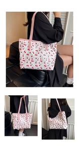 Detail view of large tote bag with red cherry print and pink straps for daily use