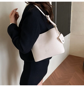 Close-up of cream leather bucket bag with matching small charm and adjustable strap