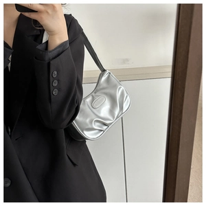 Close-up of metallic silver hobo bag featuring pleated bottom and a stylish oval logo patch