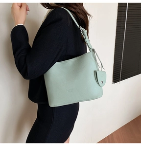 Detail of mint green lychee grain leather bucket bag with brand embossing and matching strap