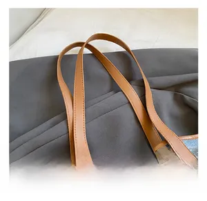 Close-up of comfortable brown faux leather handles and stitching on a tote bag