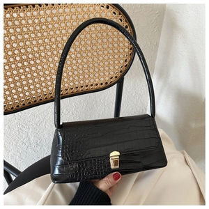 Close-up of black crocodile pattern embossing with golden metal snap button closure