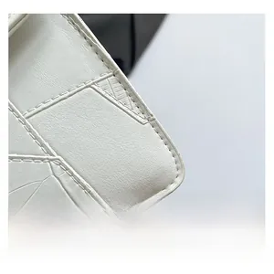 Close-up of white croc-embossed leather texture and precise stitching on the luxury bag