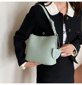Detail of mint green lychee grain leather bucket bag with debossed logo and adjustable strap