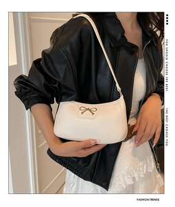 White litchi pattern leather armpit bag with gold bow knot detail on model's shoulder