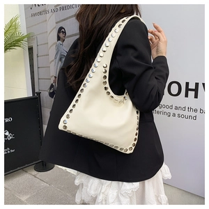 Close-up of creamy white faux leather shoulder bag featuring decorative metal rivets
