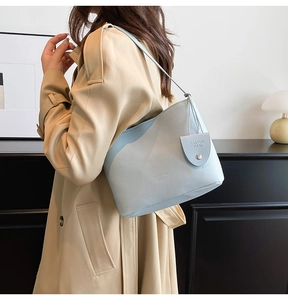 Detail view of a light blue bucket bag with pebble leather texture and metal buckle charm