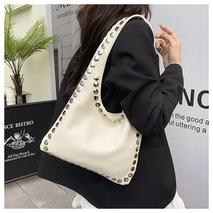 Detail view of cream leather hobo bag with silver rivet studs worn by a model
