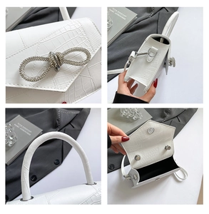 Detail of white crocodile pattern handbag with crystal bow and adjustable shoulder strap