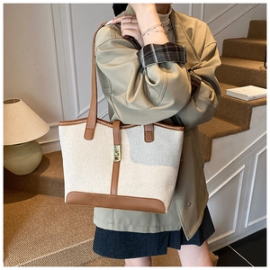 Detail of canvas tote bag with brown leather trim and golden metal clasp on a model