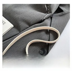 Close-up of comfortable cream lychee grain leather handbag strap on a grey suit