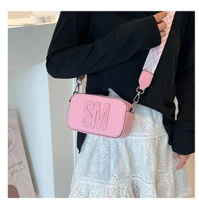 Vue détaillée du sac bandoulière rose avec gaufrage et large sangle tissée confortable