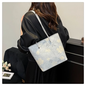 Floral embroidery tote bag detail showing large capacity and shoulder strap in lifestyle setting