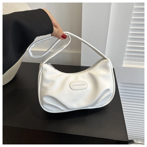 Detail of white pleated moon bag showing the leather texture and fashion brand tag
