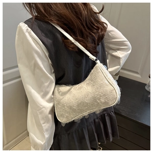 Detail showing white sequin fabric texture and leather shoulder strap of an underarm bag