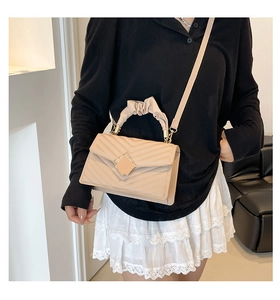 Detail of cream V-quilted small square bag with ruched handle and gold diamond buckle