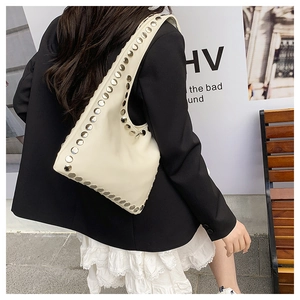 Detail shot of chic cream leather tote featuring silver rivets on strap and body