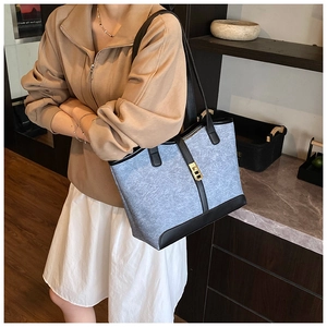 Detail of grey-blue felt tote bag with black leather trim and golden metal clasp buckle