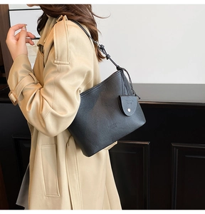 Close-up of black leather bucket bag with textured finish and brand logo detail