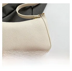 Detail showing the creamy white lychee grain texture and gold buckle of the shoulder bag