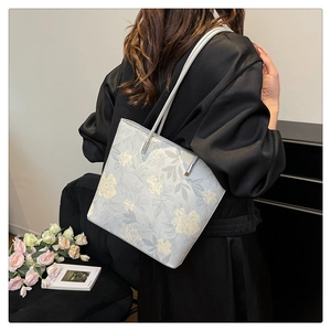 Detailed close-up of light blue floral tote bag with elegant hand-painted flower patterns