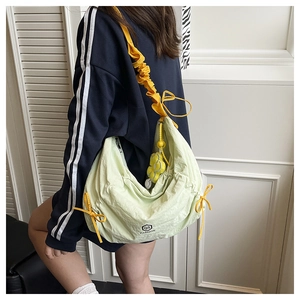 Detail of light green nylon bag showing yellow drawstring straps and printed logo