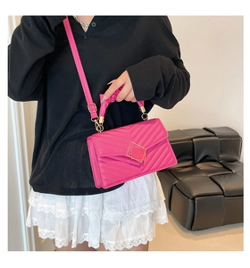 Detail view of hot pink quilted shoulder bag with gold metal buckle and pleated handle